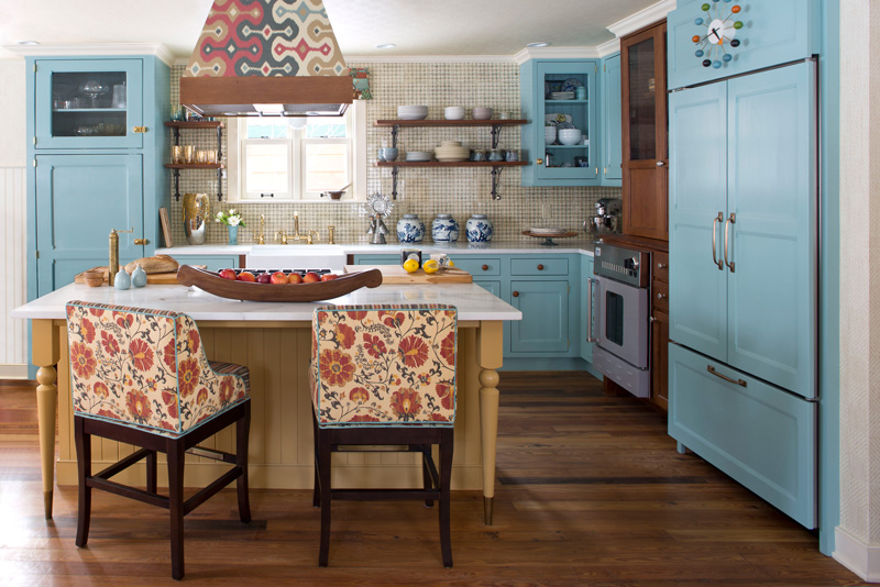 Beautiful interior design in kitchen with blue cabinets and patterned chairs at island