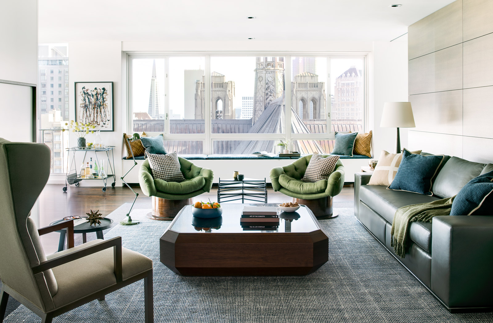 Beautiful interior design in high-rise living room with green leather couch and armchair seating