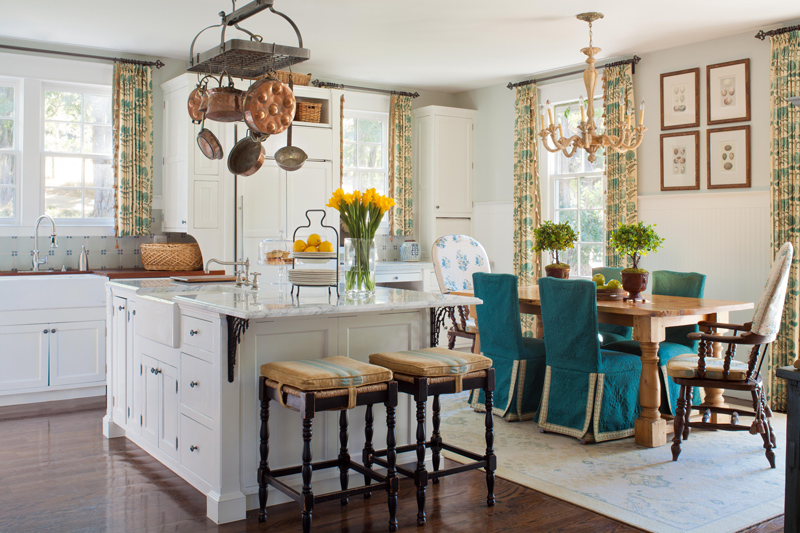 Beautiful interior design in open floor plan kitchen with island and teal chairs at wood dining table