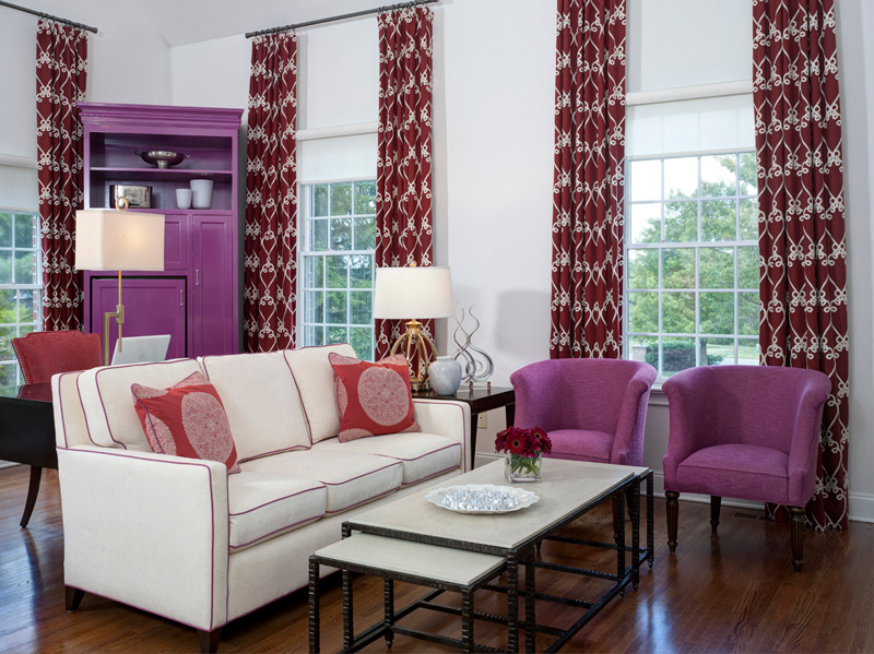 Beautiful interior design in living room with white couch, purple club chairs and maroon patterned curtains